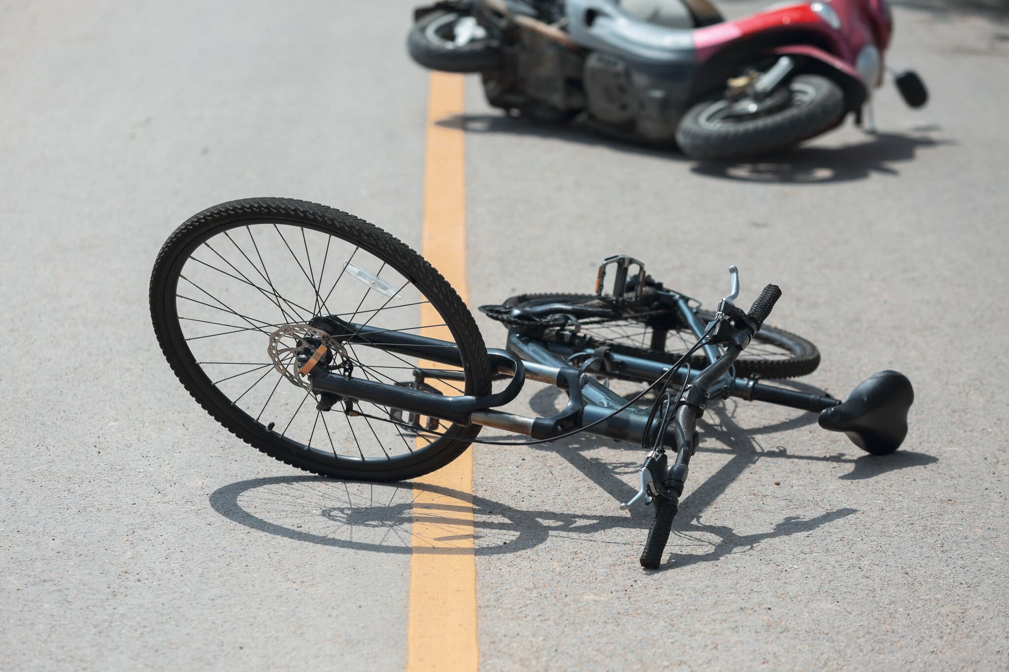 A bicycle laying on the ground after being hit by a motorcycle.