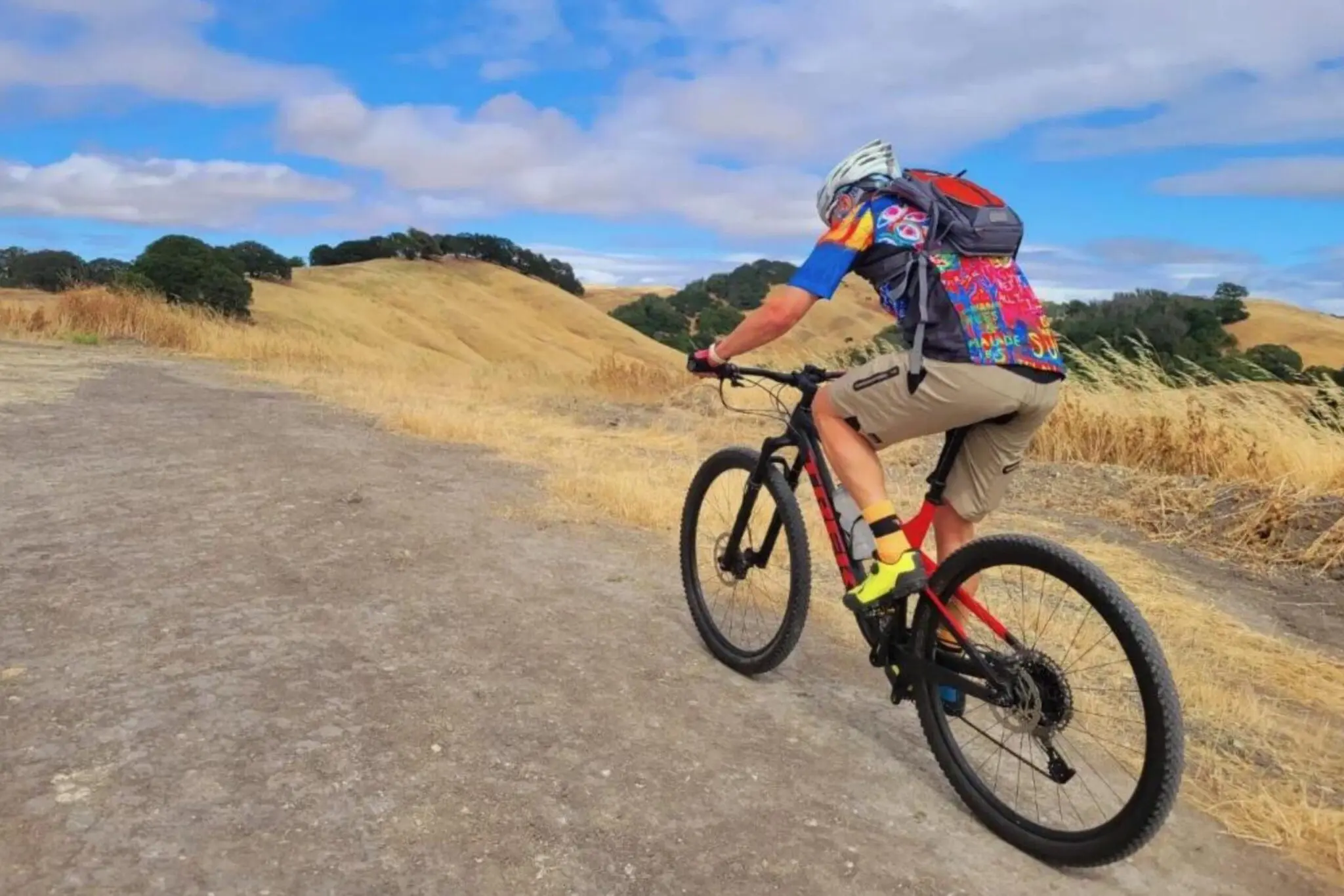 A man riding a bike down the side of a dirt road.