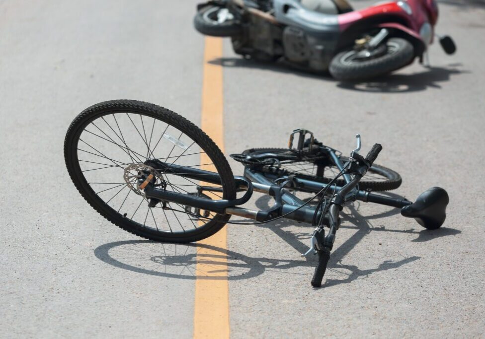 A bicycle laying on the ground after being hit by a motorcycle.